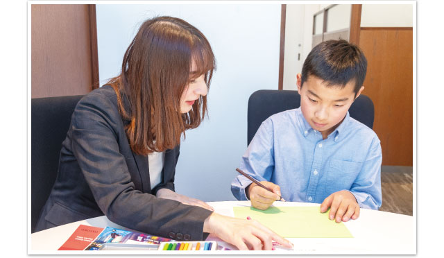 ジェスチャーをしながら話す小学生とそれを聞く講師